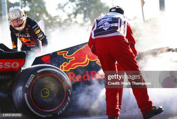 Max Verstappen of the Netherlands and Oracle Red Bull Racing and a track marshal tend to the fire in his car after he retired from the race during...