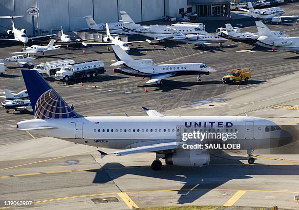 United Airlines Airbus A319 airplane waits on a taxiway to takeoff alongside private jets at John Wayne Airport in Santa Ana, California, February...