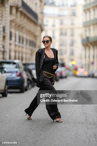 Diane Batoukina @diaanebt wears black sunglasses from Chanel, a black transparent V-neck tank-top from Saint Laurent Paris, a black oversized blazer...