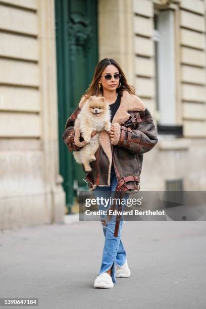 Patricia Gloria Contreras wears gold and brown sunglasses, gold metallic large LV monogram earrings from Louis Vuitton, a white and pale pink pearls...