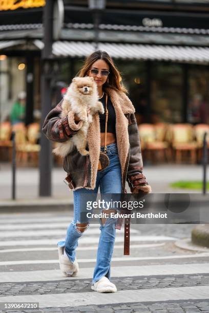 Patricia Gloria Contreras wears gold and brown sunglasses, gold metallic large LV monogram earrings from Louis Vuitton, a white and pale pink pearls...
