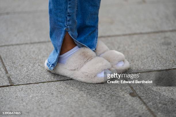 Patricia Gloria Contreras wears blue denim flared slit / split pants, white socks, white fluffy shoes / sandals, during a street style fashion photo...