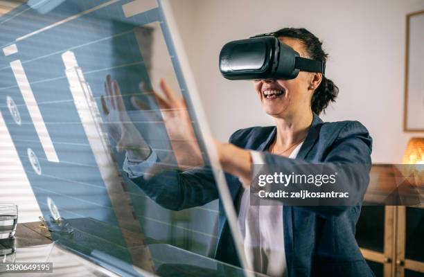 businesswoman interacting with a virtual reality headset - digital transformation stock pictures, royalty-free photos & images