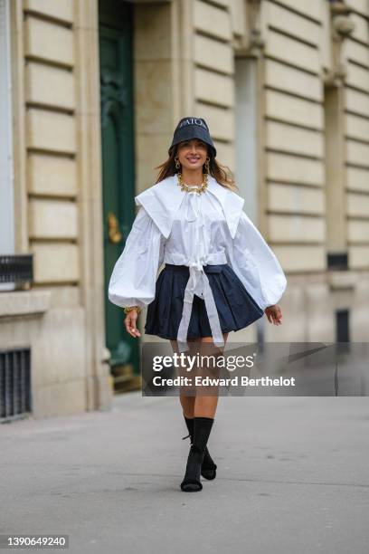 Patricia Gloria Contreras wears a black denim with embroidered white inscriptions bob from Patou, gold large chain pendant earrings, a matching gold...