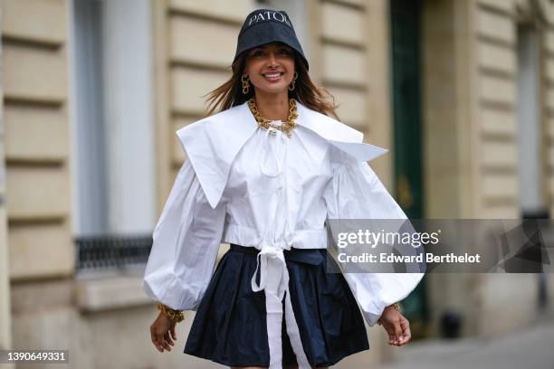 Patricia Gloria Contreras wears a black denim with embroidered white inscriptions bob from Patou, gold large chain pendant earrings, a matching gold...