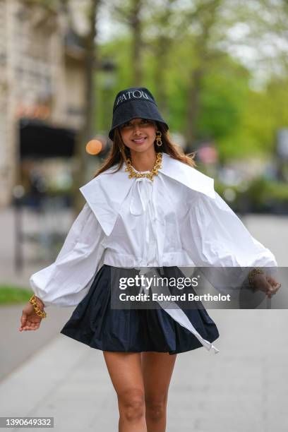 Patricia Gloria Contreras wears a black denim with embroidered white inscriptions bob from Patou, gold large chain pendant earrings, a matching gold...