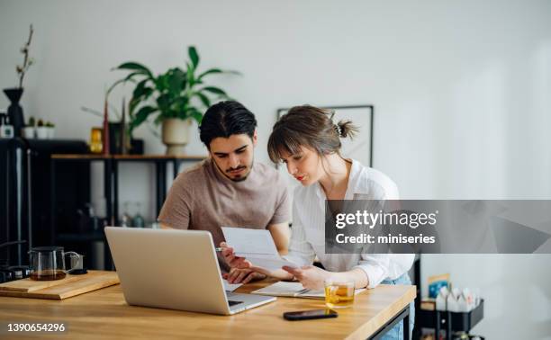 serious couple paying bills at home - electricity bill stockfoto's en -beelden