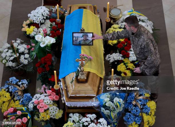 Soldier places the photograph of Ukrainian soldier Andriy Zagornyakon on his flag draped casket during his funeral on April 10, 2022 in...