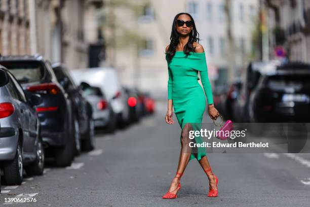 Emilie Joseph @in_fashionwetrust wears black sunglasses, rhinestone earrings, a green ribbed wool high neck / slit tube midi dress, a pink shiny...