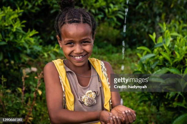 afrikanisches kleines mädchen, das frisches wasser trinkt, ostafrika - african girl drinking water stock-fotos und bilder