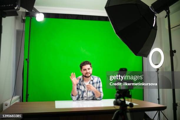 joven guapo vlogging en un estudio sobre fondo verde - chroma key fotografías e imágenes de stock