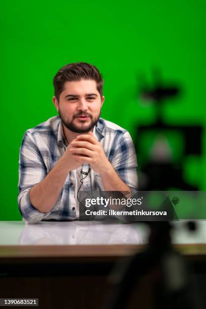 young handsome man vlogging in a studio against green background - multimedia presentation stock pictures, royalty-free photos & images