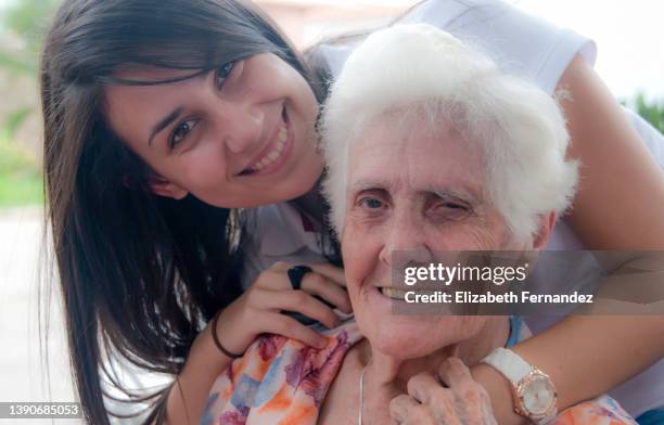 granddaughter hugs senior old grandma outdoors - venezuelan girls stock pictures, royalty-free photos & images