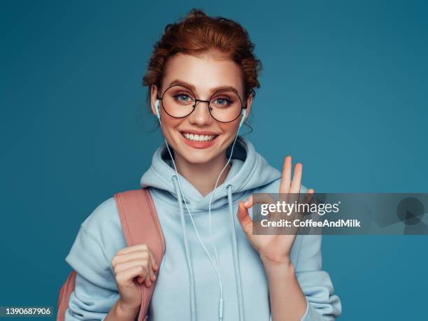 close-up portrait of a young pretty girl in a blue hoodie - ok hand sign stock pictures, royalty-free photos & images