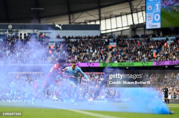 Trent Alexander-Arnold of Liverpool battles for possession with Phil Foden of Manchester City as a flare is thrown onto the pitch during the Premier...