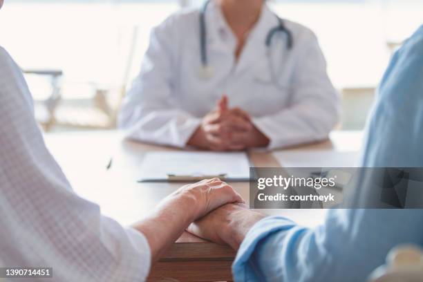 mature couple holding hands at a doctors office - couple counselling stock pictures, royalty-free photos & images