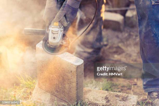 man outdoors cutting concrete block with circular saw for building a garden stairs - circular saw stockfoto's en -beelden