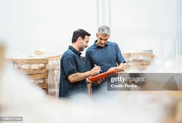 mature workers taking inventory of packaged meat in the warehouse - koelkast stockfoto's en -beelden