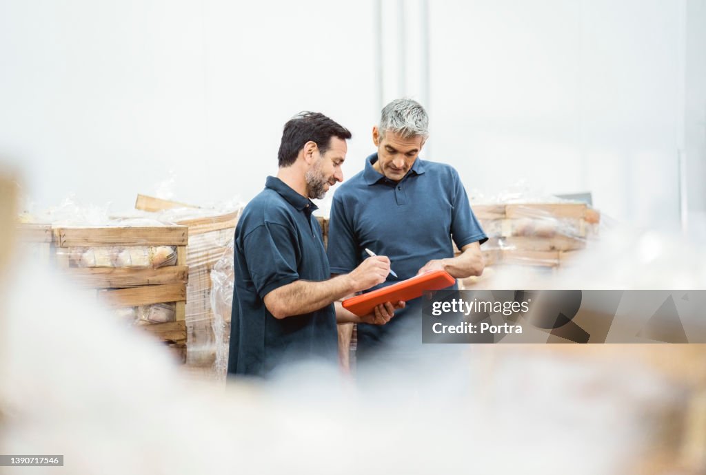 Mature workers taking inventory of packaged meat in the warehouse