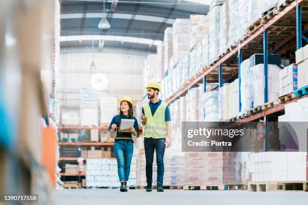 two employees checking inventory on warehouse racks - directeur stockfoto's en -beelden