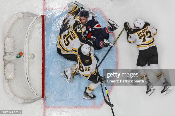 Garnet Hathaway of the Washington Capitals collides with goalie Linus Ullmark of the Boston Bruins during the second period at Capital One Arena on...