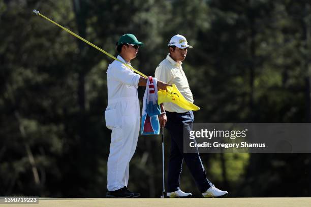 Hideki Matsuyama of Japan and caddie Shota Hayafuji look on from the 18th green during the final round of the Masters at Augusta National Golf Club...