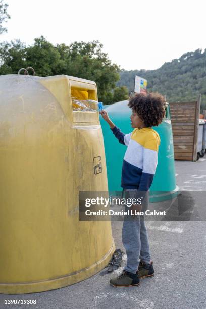 boy putting a plastic bottle into a dumpster for recycling - mixed recycling bin stock pictures, royalty-free photos & images