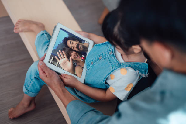 young girl having video calls with family on digital tablet together with her father - zoom stock pictures, royalty-free photos & images
