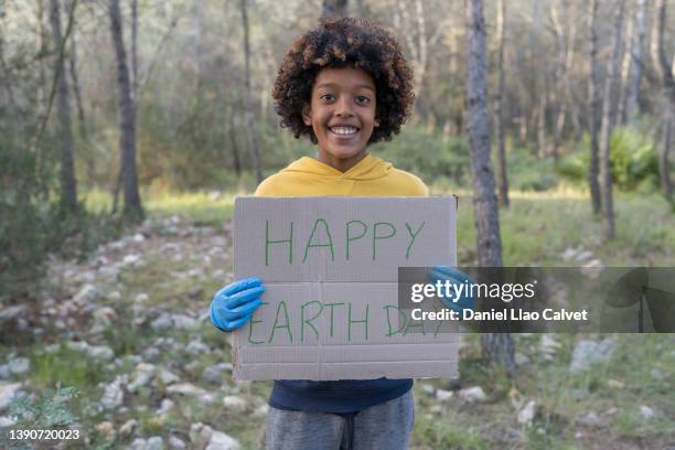 african american boy holds up a "happy earth day - happy earth day stock-fotos und bilder