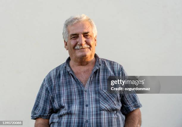 retrato de cerca de un hombre maduro sobre una pared blanca, foto a la luz del día - arab old man fotografías e imágenes de stock