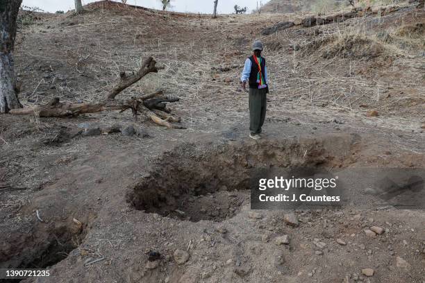 Addisu Mamaye Ayane stands over several large holes that mark the locations of mass graves all total containing the remains of 36 individuals...