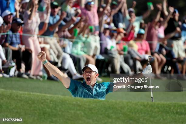 Rory McIlroy of Northern Ireland reacts after chipping in for birdie from the bunker on the 18th green during the final round of the Masters at...