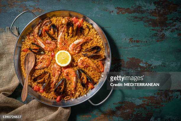 paella de marisco receta de dieta mediterránea con camarones, calamares y mejillones sobre madera verde rústica - catalonia fotografías e imágenes de stock