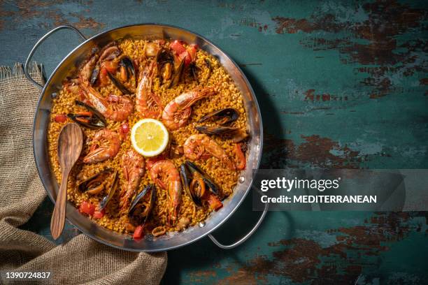 seafood paella mediterranean diet recipe with shrimp, squid and mussels on rustic green wood - mexilhão imagens e fotografias de stock