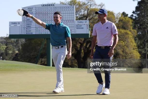 Rory McIlroy of Northern Ireland and Collin Morikawa acknowledge the fans as they walk off the 18th green after finishing their round during the...