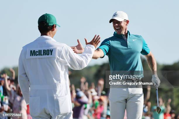 Rory McIlroy of Northern Ireland and caddie Harry Diamond celebrate after chipping in for birdie from the bunker on the 18th green during the final...