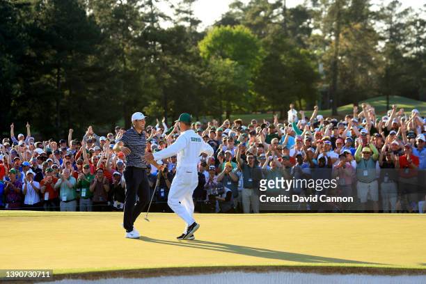 Scottie Scheffler and caddie Ted Scott embrace on the 18th green after winning the Masters at Augusta National Golf Club on April 10, 2022 in...