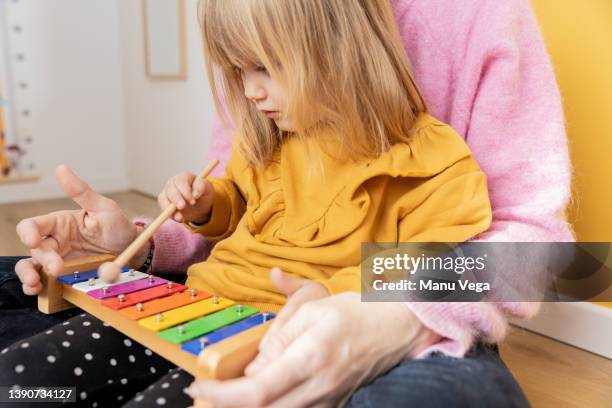 mother teaching her little daughter to play a simple melody on the xylophone. - xylophone stock pictures, royalty-free photos & images