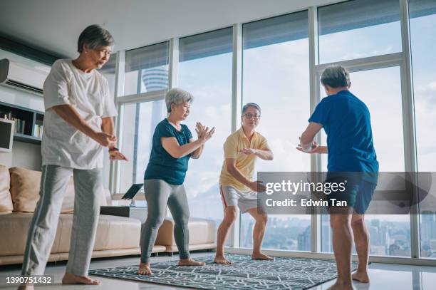asian chinese senior man teaching his senior friends tai chi enjoying home workout during evening in apartment living room - tai chi shadow stock pictures, royalty-free photos & images