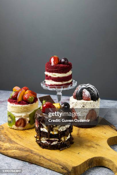 red black fruit cake, strawberry and chocolate mini cakes, fruit cake and chocolate biscuit celebration cake on wooden surface, various mini cakes - coffee cake stockfoto's en -beelden