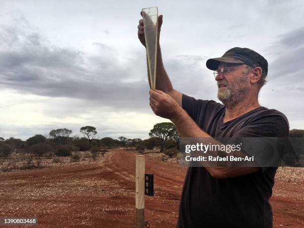 australian farmer measuring the rain fall in the outback of western australia - farmer australia ストックフォトと画像