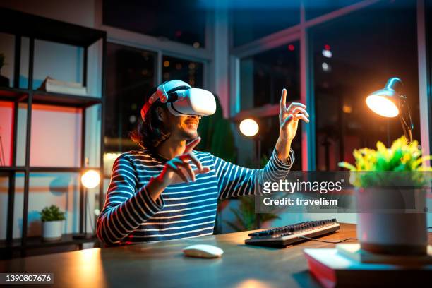 creative asian young male man wearing smart virtual  glasses and joining business meeting on augmented reality metaverse working space,asia man using a vr headset to explore virtual space video conference abroad country at night - young businessman using a virtual screen stockfoto's en -beelden