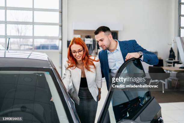 attractive middle age couple buying car in showroom - försäljning av begagnad bil bildbanksfoton och bilder
