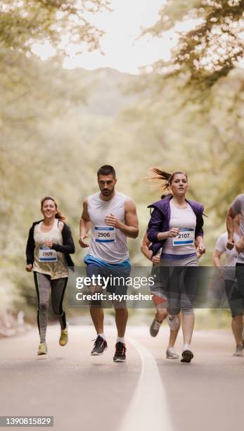 group of people running a marathon on asphalt road in nature. - road running stock pictures, royalty-free photos & images
