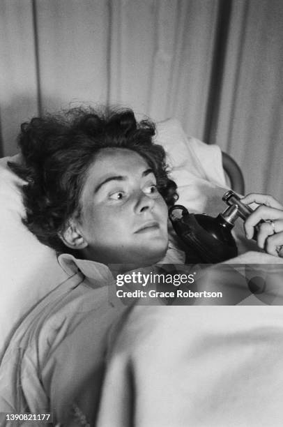 Pregnant woman holding a pain relief breathing apparatus for nitrous oxide during labor at a birth centre, UK, 1956. Original Publication: Picture...