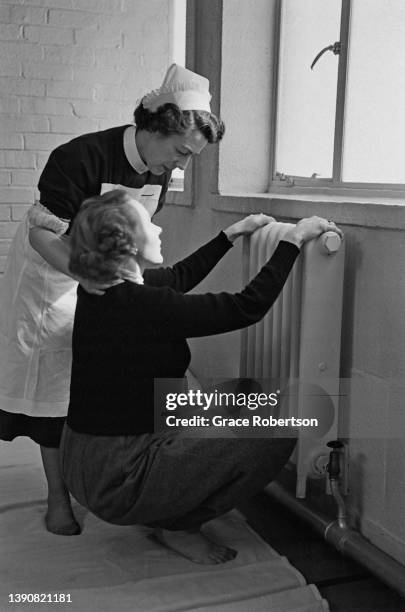 With the help of a midwife, a pregnant woman practicing relaxation and breathing techniques for pain relief at an antenatal class in preparation for...