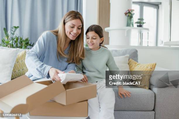 smiling mother and daughter opening a delivery box - opening delivery stock pictures, royalty-free photos & images