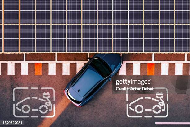 aerial view of electric car parking in charging station with solar panels. - electric cars stock pictures, royalty-free photos & images