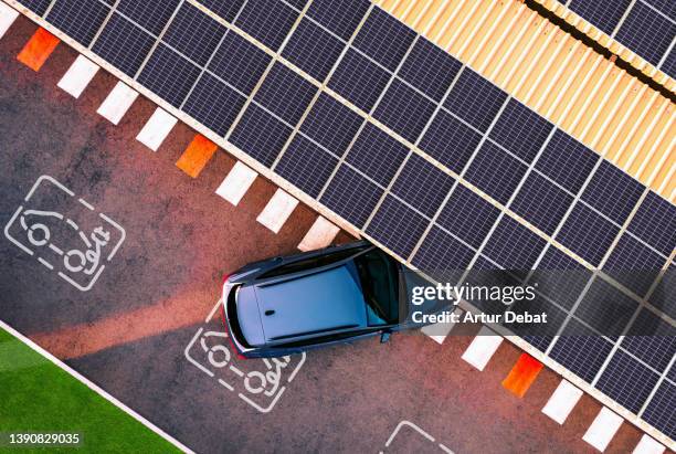 aerial view of electric car parking in charging station with solar panels. - parkplatz stock-fotos und bilder