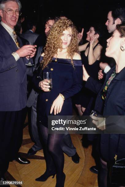 American actress and singer Bernadette Peters wearing a midnight blue off-the-shoulder jacket with brass buttons and a black sequin miniskirt,...
